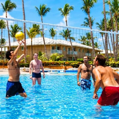 groupe d'hommes jouant au volley ball dans la piscine, palmiers, ciel bleu