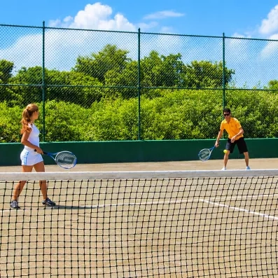 un homme et une femme jouant au tennis, filet, court de tennis, végétation luxuriante