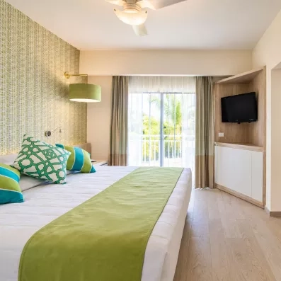 chambres double standard 2 lits avec dessus lit vert, table basse blanche, deux luminaires blancs, un tableau et porte d'entrée au fond