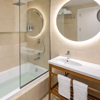 salle de bains avec vasque en marbre, un grand miroir et des serviettes 