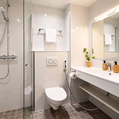 Salle de bain moderne et lumineuse d'une chambre au Mondi Club Sodankylä en Laponie avec douche italienne et vasque.