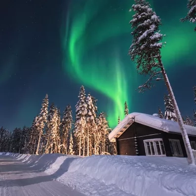 Chalet traditionnel en bois sous les aurores boréales au Mondi Club Sodankyla en Laponie