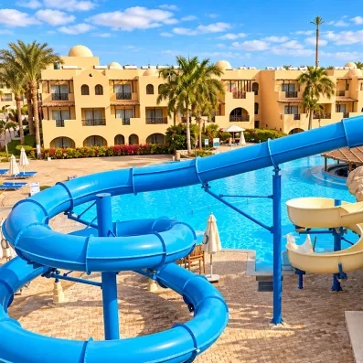 Piscine avec toboggans bleus et bâtiments ocres au Mondi Club Stella Garden, Hurghada, Egypte.
