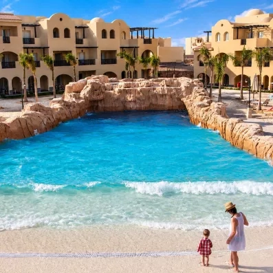 Piscine à vagues artificielle avec cascade et palmiers au Mondi Club Stella Garden, complexe hôtelier à Hurghada, Égypte.