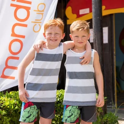 Enfants souriants devant le drapeau Mondi Club lors de vacances en famille à Hurghada, Égypte.