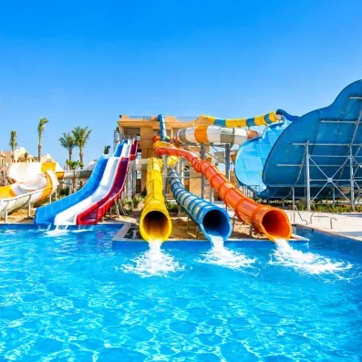 Toboggans aquatiques multicolores à sensations fortes débouchant dans la piscine de l'aquapark d'Hurghada.