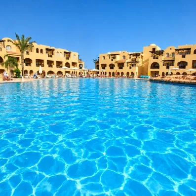 Vue sur la grande piscine turquoise et les bâtiments ocre du Mondi Club Stella Gardens à Hurghada