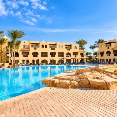 Grande piscine bleue et bâtiments ocre au Mondi Club Stella Garden, séjour balnéaire à Hurghada, Égypte.