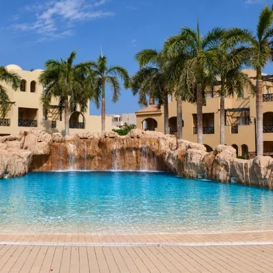 Piscine à vagues artificielle avec cascade et palmiers au Mondi Club Stella Garden, complexe hôtelier à Hurghada, Égypte.