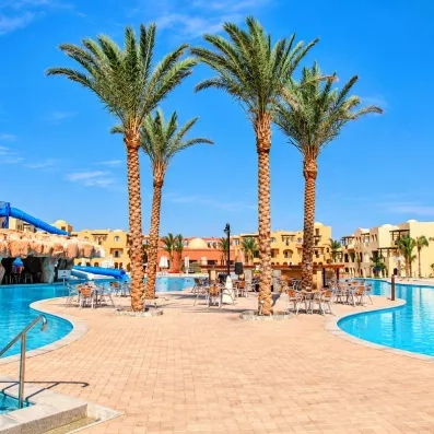 Grande piscine avec palmiers, bar-terrasse et toboggans du complexe hôtelier Mondi Club Stella Gardens Resort à Hurghada, Égypte.