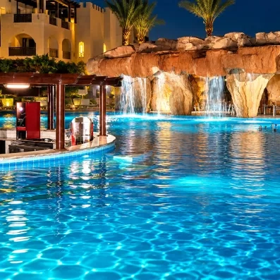 Grotte artificielle avec cascades éclairées dans la piscine de nuit au Mondi Club Stella Garden.