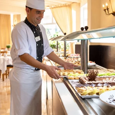 Chef pâtissier disposant des gâteaux et desserts au buffet du restaurant du Mondi Club Thalassa Mahdia en Tunisie.