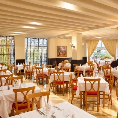 Vue d'ensemble de la grande salle à manger du Mondi Club Thalassa Mahdia avec chaises en bois et nappes blanches.