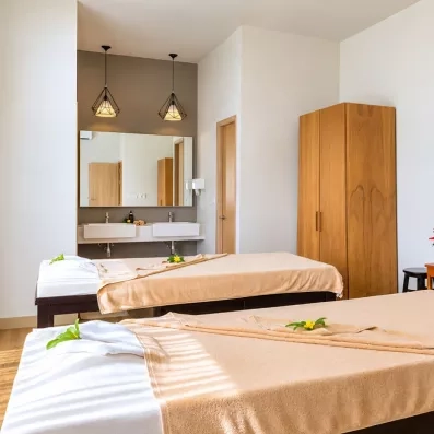 Une salle de soin comprenant deux tables de massage et un grand placard en bois.