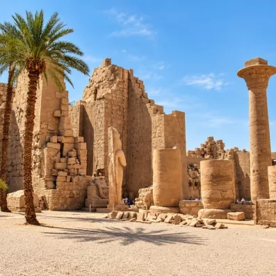 Statues de pharaons et colonnes monumentales du complexe de Karnak à Louxor sous un ciel bleu en Égypte.