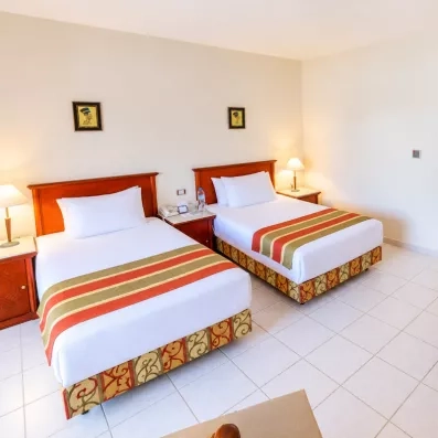 Vue en angle d'une chambre familiale avec deux lits simples à l'hôtel Blend Club Aqua Resort Égypte.