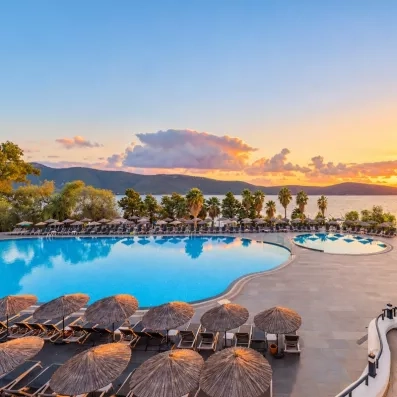 Une immense piscine extérieure offrant une vue panoramique sur la mer au coucher du soleil.