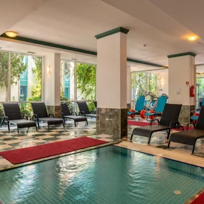 Un espace de détente intérieur avec des transats au bord d'une piscine de relaxation.