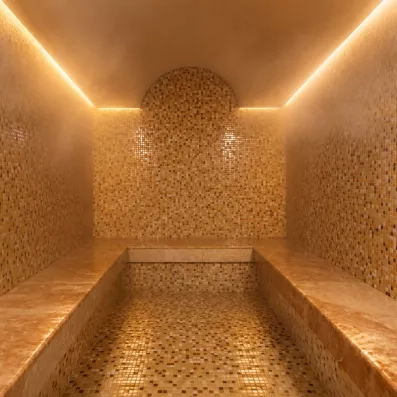 Un sauna ou bain de vapeur épuré entièrement revêtu de mosaïques de tons beiges.
