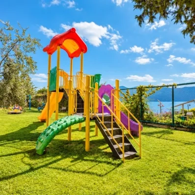 Une aire de jeux extérieure avec un toboggan installée sur une pelouse ensoleillée.