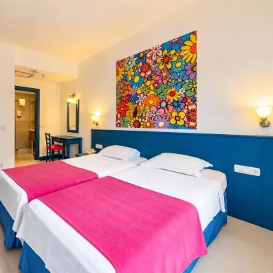 Une vue d'ensemble de la chambre montrant l'entrée, le coin bureau et l'accès à la salle de bain.