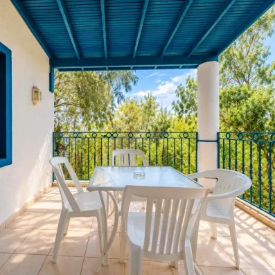 Une terrasse ombragée sous une pergola bleue, équipée d'une table et de chaises.