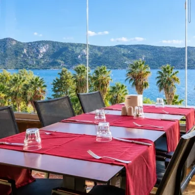 Un gros plan sur une table, située juste devant une vitre donnant sur des palmiers et la mer.