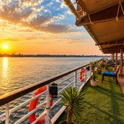 Coucher de soleil doré sur le Nil observé depuis le pont en teck d'un bateau de croisière en Égypte.