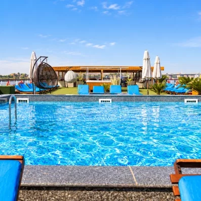 Pont supérieur avec piscine, transats bleus et fauteuils suspendus pour une croisière détente en Égypte.