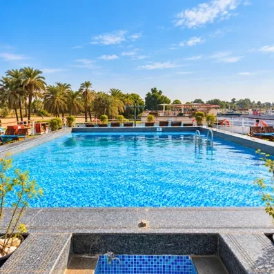 Piscine d'eau bleue sur le pont supérieur d'un navire de croisière bordé de palmiers sur le Nil.