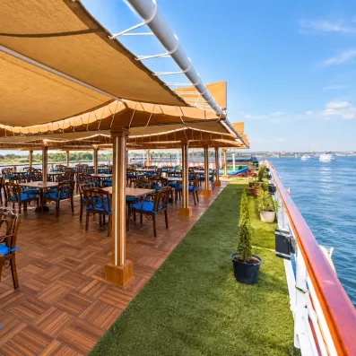 Espace restauration ombragé sur le pont supérieur avec tables en bois et vue sur le Nil.