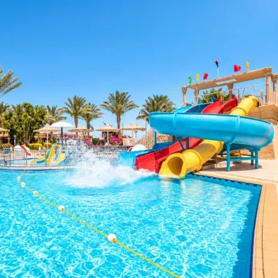 Parc aquatique avec toboggans colorés et palmiers pour des vacances en famille à l'hôtel AMC Hurghada.