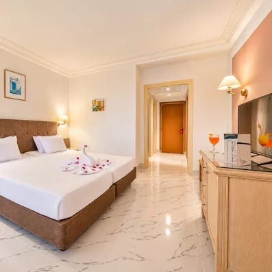 Intérieur lumineux d'une chambre d'hôtel à Djerba avec vue sur le mobilier en bois et télévision.