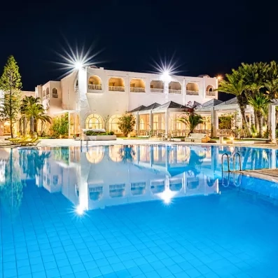 Piscine illuminée de nuit à l’hôtel Djerba Golf Resort & Spa, destination de vacances relaxantes en Tunisie.