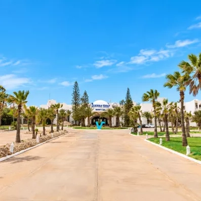 Allée principale bordée de palmiers menant à l'entrée de l'hôtel Djerba Golf Resort & Spa en Tunisie.