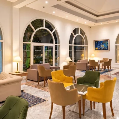 Lobby d'hôtel luxueux à Djerba avec mobilier coloré, sol en marbre et grandes baies vitrées lumineuses.
