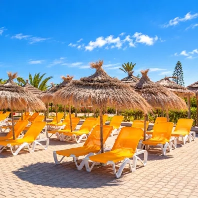 Espace détente avec parasols en paille et transats jaunes à l'hôtel Djerba Aqua Resort