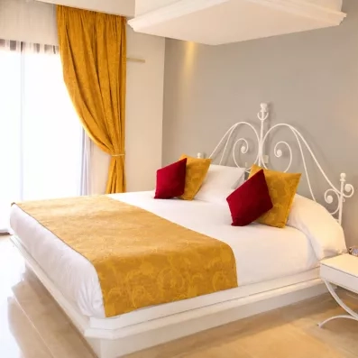 Lit king-size élégant avec jeté de lit doré dans une chambre de l'hôtel Djerba Aqua Resort en Tunisie.