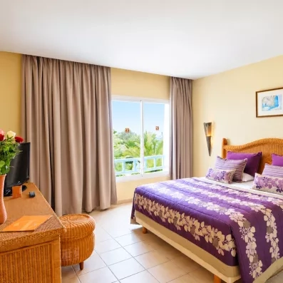 Chambre d'hôtel lumineuse au Djerba Resort offrant une vue sur les jardins tropicaux depuis la fenêtre.