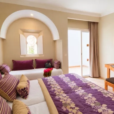 Chambre familiale au Djerba Resort avec alcôve traditionnelle, lit confortable et accès balcon ensoleillé.