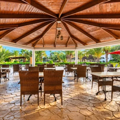 Terrasse ombragée sous une coupole en bois avec vue sur les jardins tropicaux de l'hôtel Djerba Resort.