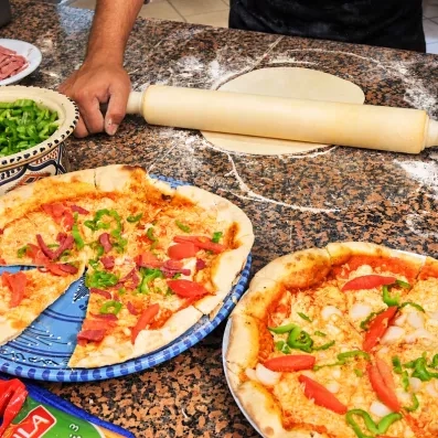 Préparation artisanale de pizzas fraîches par un chef italien dans les cuisines du Djerba Resort
