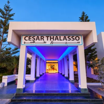 Entrée moderne illuminée de bleu de l'hôtel César Thalasso à Djerba, destination bien-être en Tunisie.