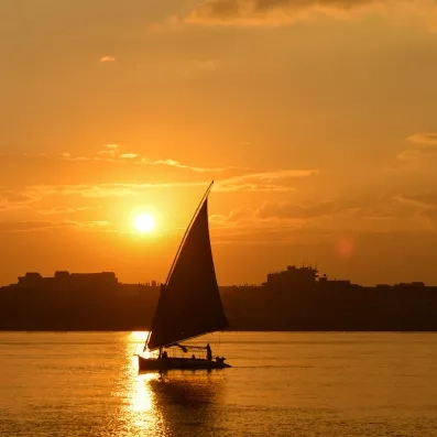 Silhouette d'une voile de felouque sur le Nil lors d'un coucher de soleil romantique à Louxor.