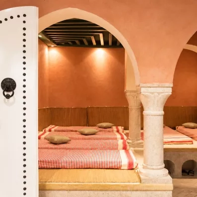 Salle de repos traditionnelle du spa avec lits de relaxation et colonnes en pierre sculptée.