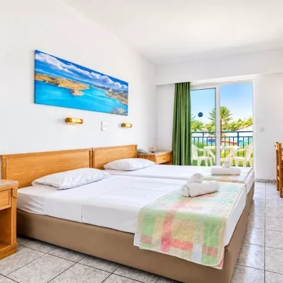 Chambre avec deux lits collés, une tête de lit en bois, un tableau d'une plage et une porte fenêtre de la terrasse