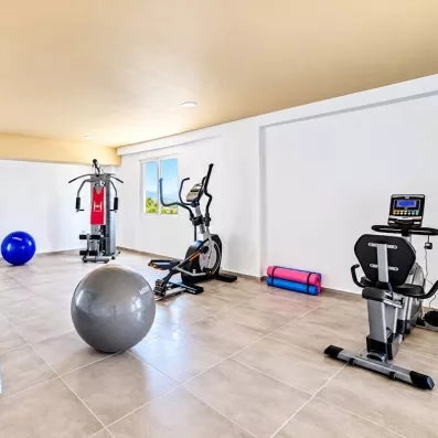 salle de fitness équipé de bicyclette, tapis, et des ballons gonflables 