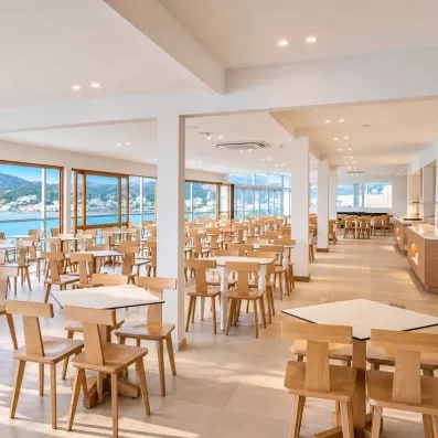 Une salle de restaurant avec des longues baies vitrées vue sur la mer.