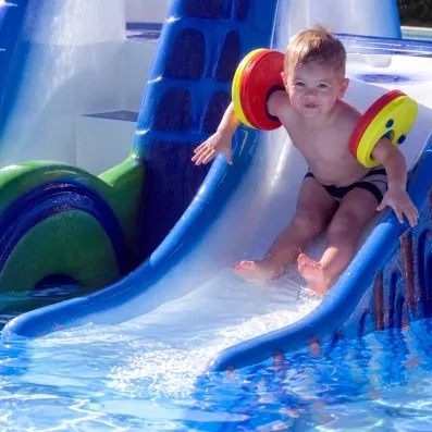 Jeune enfant glissant sur un petit toboggan de piscine au Jaz Aquamarine Hurghada, séjour familial sécurisé.