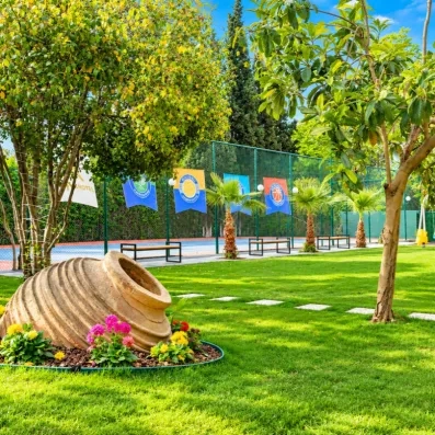 jardin verdoyant avec terrain de tennis au fond 